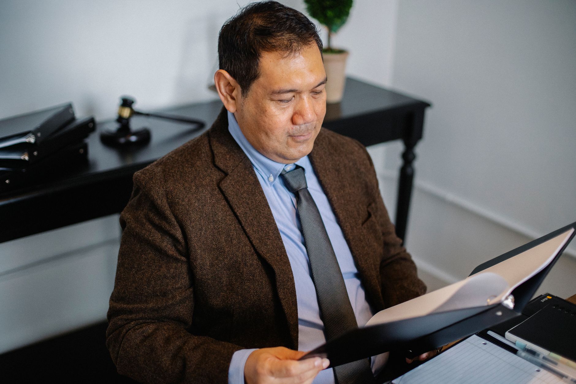 From above of serious ethnic lawyer in elegant suit checking report in folder on blurred background of office — illustrating: IT Services for Central Florida Businesses: Security, Compliance, and Cost Breakdown